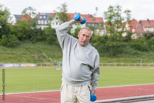 Sports in oldAn elderly man goes in for sports on the background of the stadium on a summer eveningage