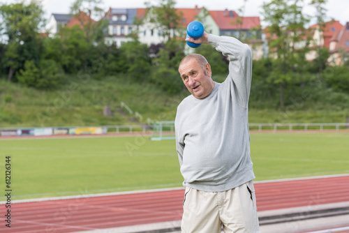 Sports in oldAn elderly man goes in for sports on the background of the stadium on a summer eveningage