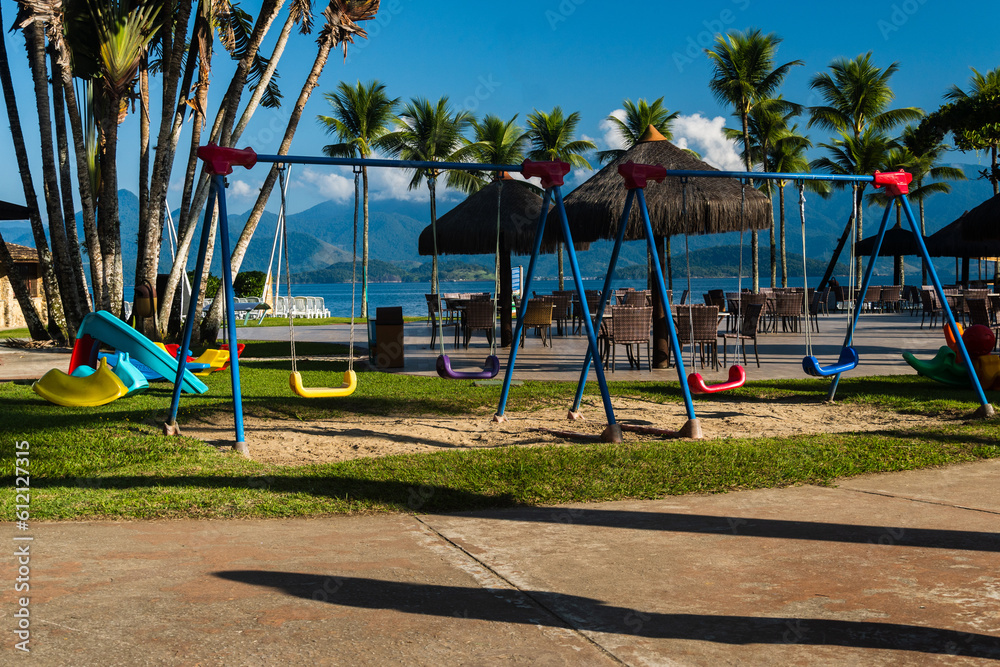 Outdoor playground with toy for children. Coconut trees and the beach in the background. Lush nature environment. Slide, tunnels among others. Playground. Sunny day Outdoor playground with toy for children. Coconut trees and the beach in the background. Lush nature environment. Slide, tunnels among others. Playground. Sunny day