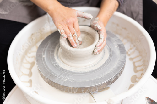 Female potter works with potter weel, craftsman hands close up. Hands of potter making clay pot