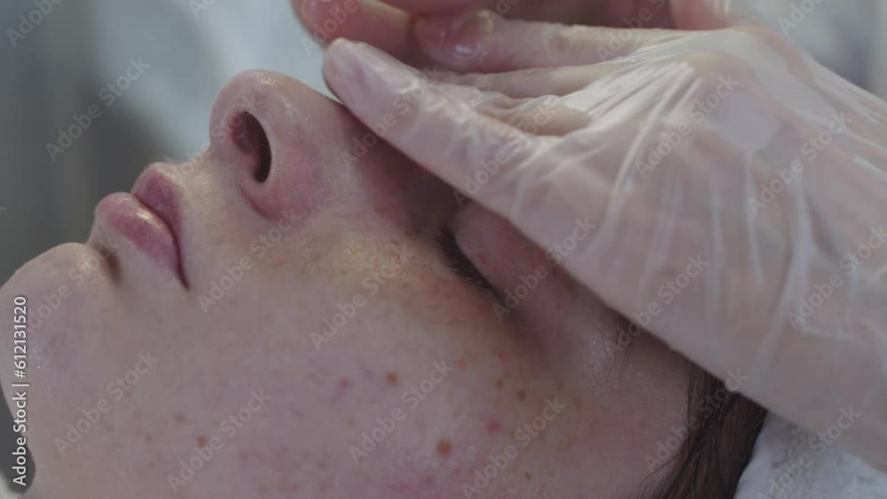 Cosmetology treatment - the master gives a soft massage to the face of her client after the procedure Cosmetology treatment - the master gives a soft massage to the face of her client after the procedure