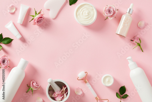 Face skin care routine products with rose blossoms on pastel pink background. Natural beauty products packaging design