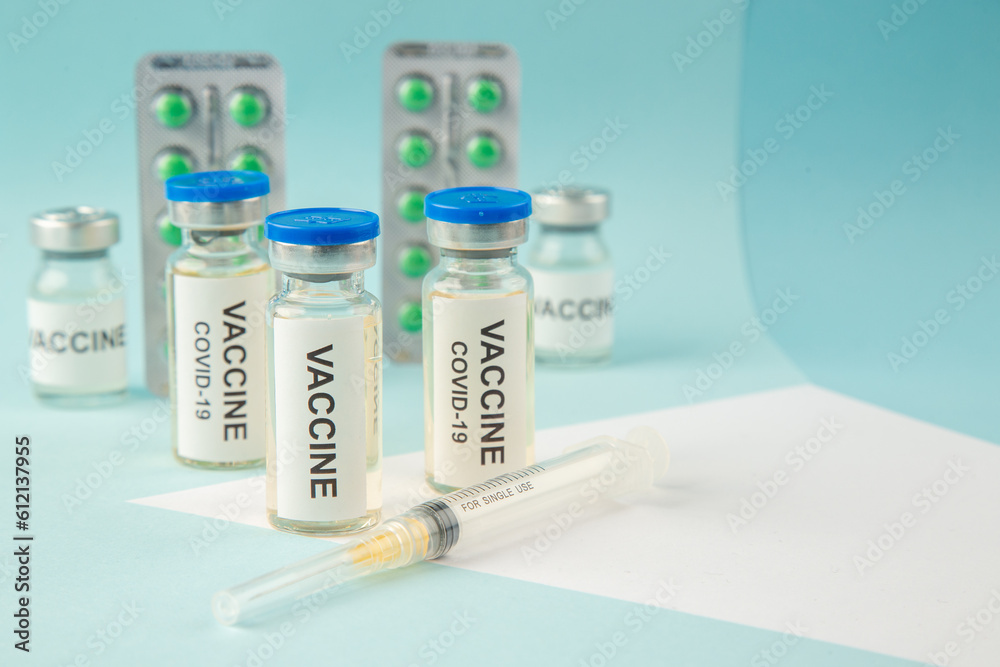 Close up view of vaccine in medical ampoules packed green pills for Covid- treatment syringe on the right side on pastel blue background Close up view of vaccine in medical ampoules packed green pills for Covid- treatment syringe on the right side on pastel blue background