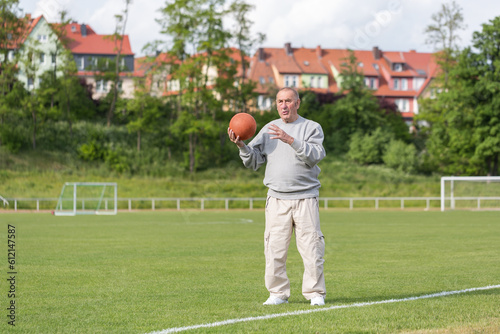 An elderly man goes in for sports on the background of the stadium on a summer evening
