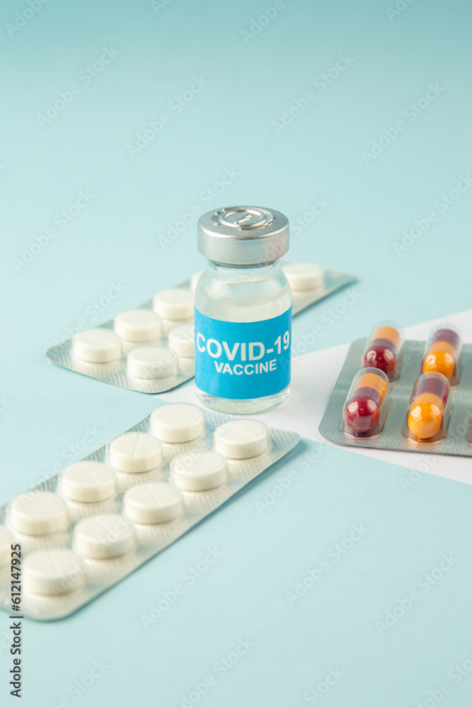 Front view of vaccine in medical ampoule packed pills capsules on pastel blue background Front view of vaccine in medical ampoule packed pills capsules on pastel blue background