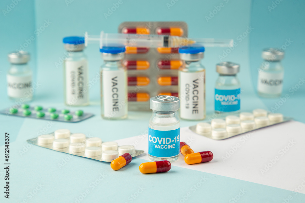 Front view of vaccine in medical ampoules packed pills and capsules for Covid- on blue background Front view of vaccine in medical ampoules packed pills and capsules for Covid- on blue background