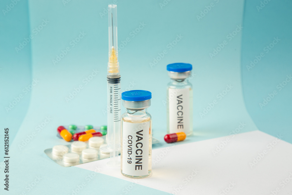Horizontal view of vaccine for treatment Covid- in medical ampoule packed pills capsules and disposable syringe on white blue mix colors background Horizontal view of vaccine for treatment Covid- in medical ampoule packed pills capsules and disposable syringe on white blue mix colors background