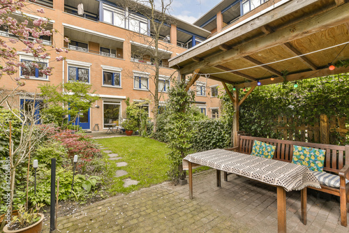 an outside area with a table and bench in the middle, surrounded by plants and trees on either side of the building