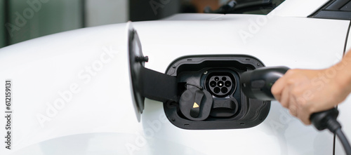 Progressive concept of hand insert an emission-free power connector to the battery of electric vehicle at home. Electric vehicle charging via cable from charging station to EV car battery