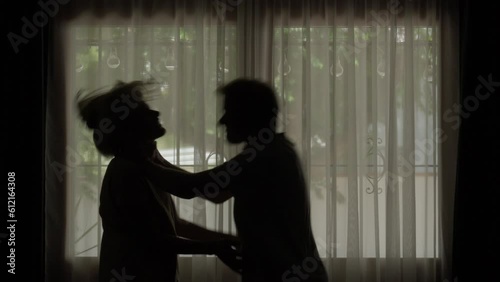 silhouette man choking a woman, strangling, about to slap her, against window background photo