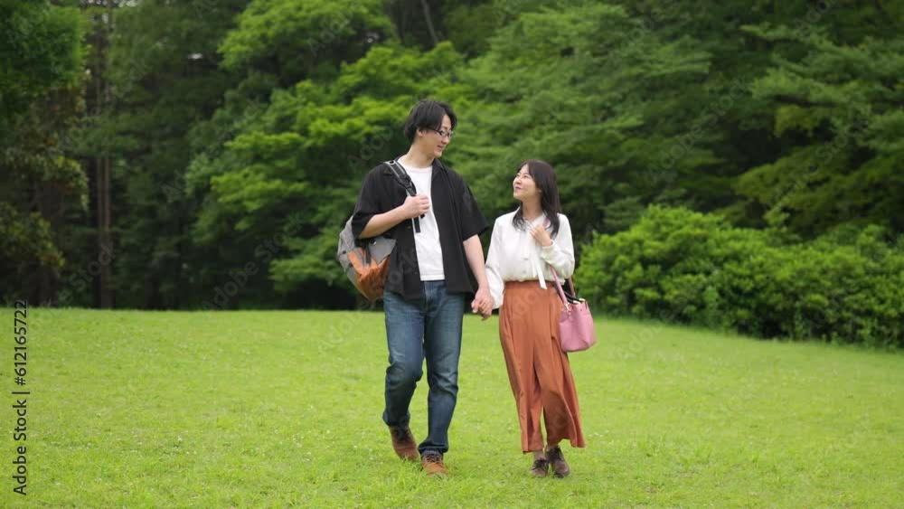 手をつないで公園を歩くカップルのスローモーション