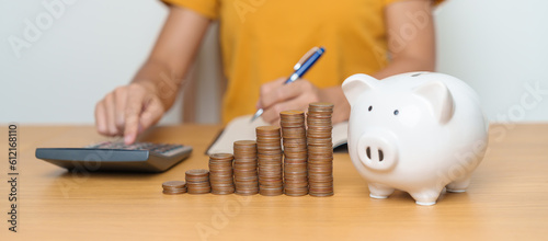Money Saving for Future Plan, Retirement fund, Pension, Investment, Wealth Business and Financial concepts. Woman Counting and calculate money with coins stack with piggy bank for deposit