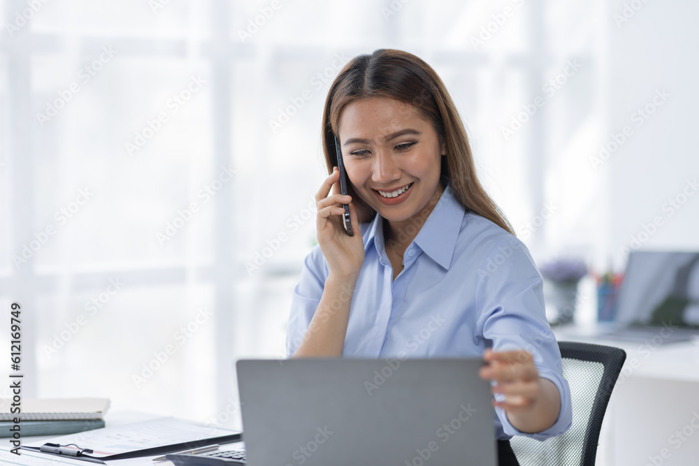 Cheerful business Asian woman freelancer making telephone call share good news about project working in office workplace, business finance concept.	