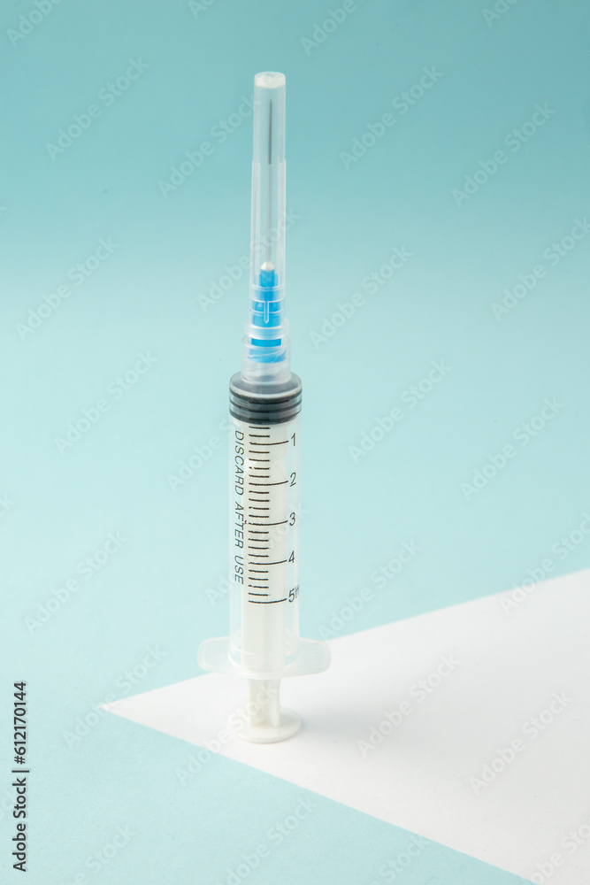 Top view of empty disposable syringe on white sheet on pastel blue background Top view of empty disposable syringe on white sheet on pastel blue background
