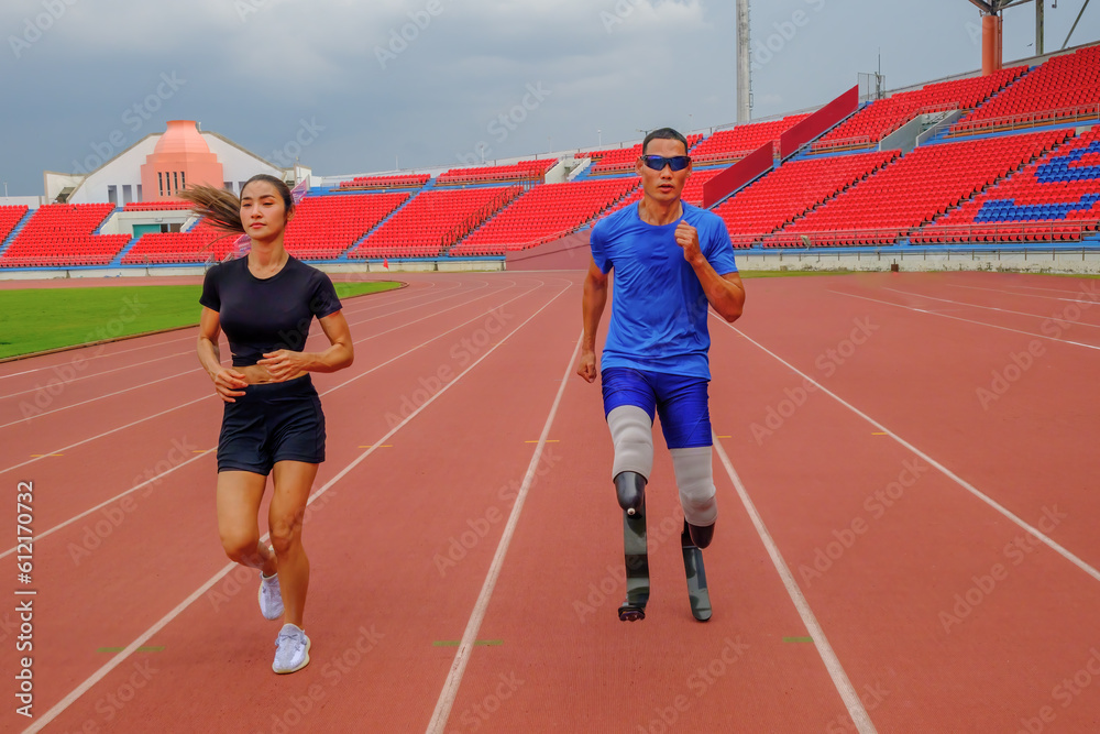 A speed runner with prosthetic running blades, alongside his female trainer, warms up with a jog on the running track before practice
