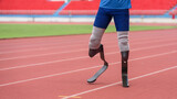 An athletic speed runner, equipped with prosthetic running blades, takes a warming-up walk on the running track before beginning his practice