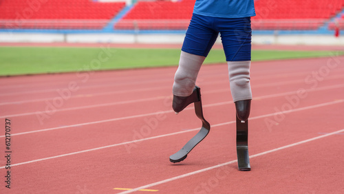 An athletic speed runner, equipped with prosthetic running blades, takes a warming-up walk on the running track before beginning his practice