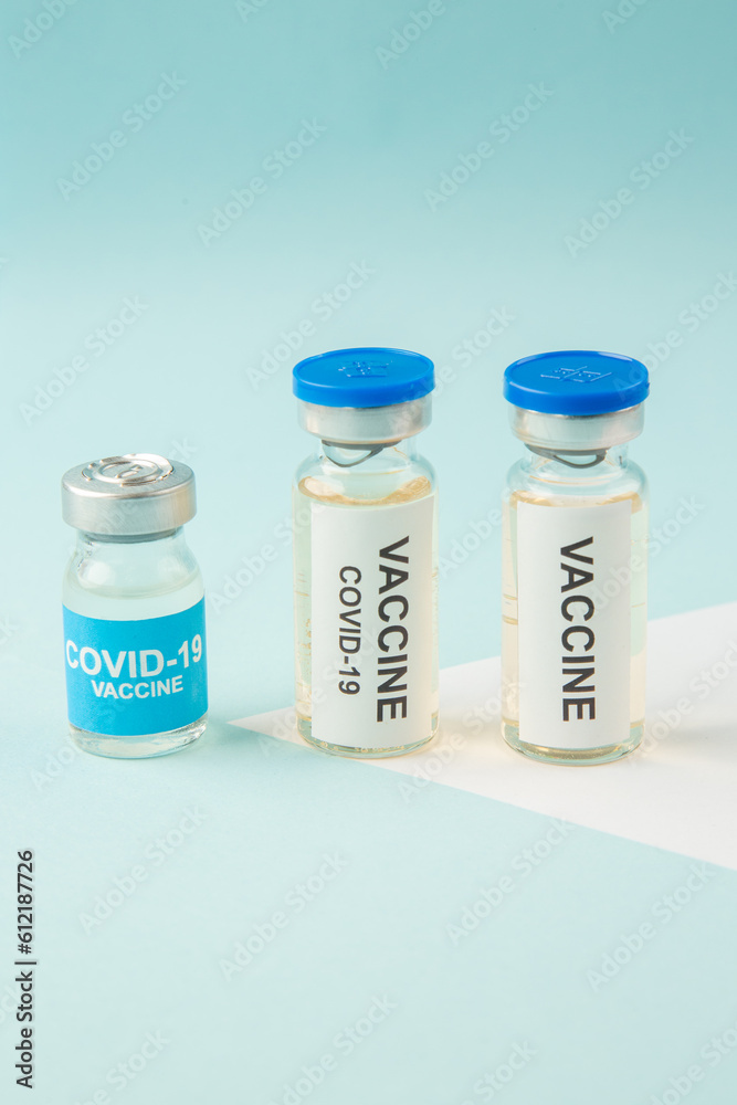 Vertical view of vaccines for treatment Covid- in medical ampoules on white blue background