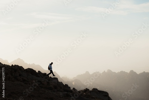 a man running up a mountain with a sky background © ramithu