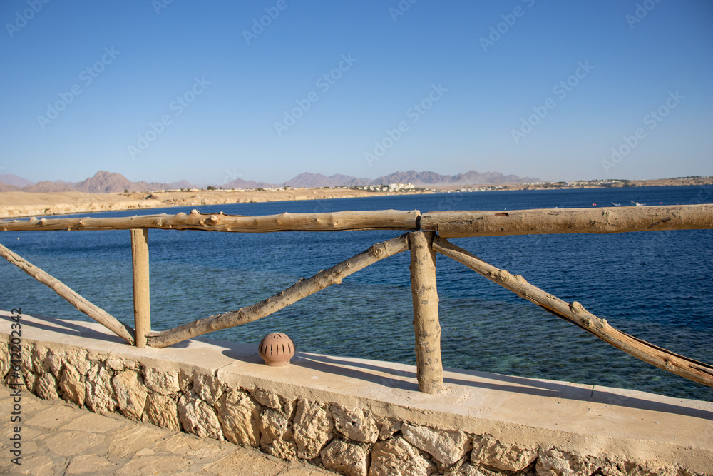 wooden hand rail with dark blue sea in the background