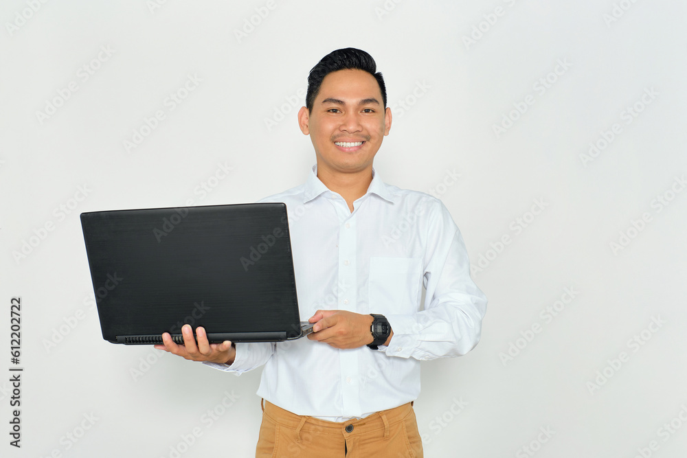 Portrait of positive young Asian man in formal wear holding laptop and looking at camera with happy smile isolated on white background Portrait of positive young Asian man in formal wear holding laptop and looking at camera with happy smile isolated on white background