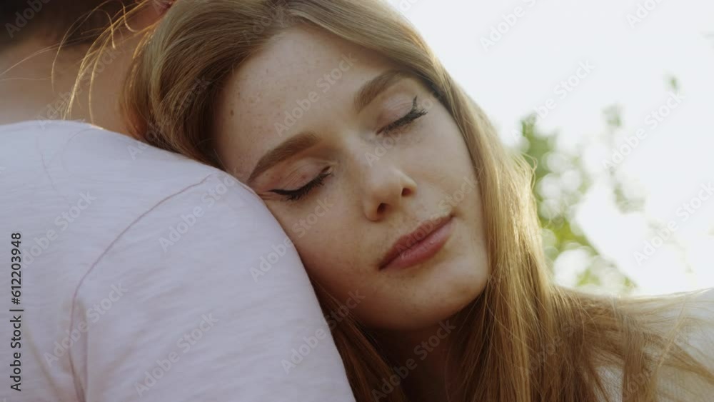 Close up view of a young lovely woma with closed eyes leaning head on her boyfriend shoulder against sunset outdoor. Love, freedom, support. Family bonding. Close up view of a young lovely woma with closed eyes leaning head on her boyfriend shoulder against sunset outdoor. Love, freedom, support. Family bonding.