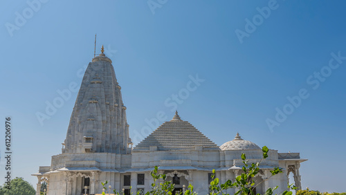 Beautiful white marble temple Birla Mandir- Lakshmi Narayana. Against the blue sky there are three domes of various shapes  oval  pyramidal  hemispherical. Columns  carved arches are visible. India.