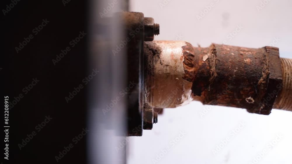 Connecting a water pipe to a solid fuel boiler. An old rusty metal heating pipe is connected to a wood-burning stove, close-up. Metal corrosion due to temperature changes and moisture Connecting a water pipe to a solid fuel boiler. An old rusty metal heating pipe is connected to a wood-burning stove, close-up. Metal corrosion due to temperature changes and moisture