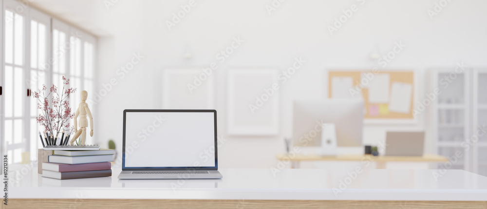 Fototapeta premium A laptop mockup on a white table over blurred background of a modern bright office.