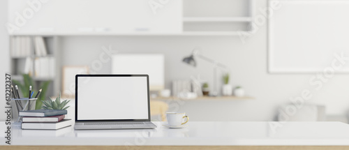 A laptop mockup on white table over blurred modern white office in background.