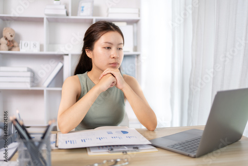 Young Asian female student watching teacher's live performance or video call on laptop in classroom at home, Conversations with teachers and classmates, Online learning, Study at your own home.