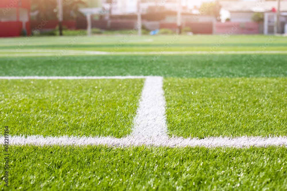Selective focus to white lines on green artificial grass football fields. Artificial turf soccer field, green background. Outdoor field.