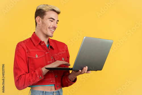 Stylish gay man smiling while using a laptop