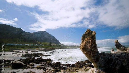 Rocky beach with rolling waves and mountain backdrop in scenic Hermanus photo