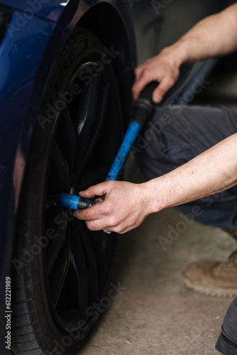Close-up of mechanic change tires on a car near his garage. Woking outdoors © Aleksandr