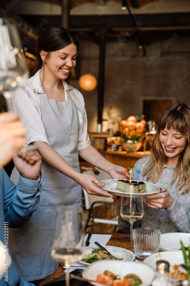 Cheerful blonde woman celebrating birthday in restaurant