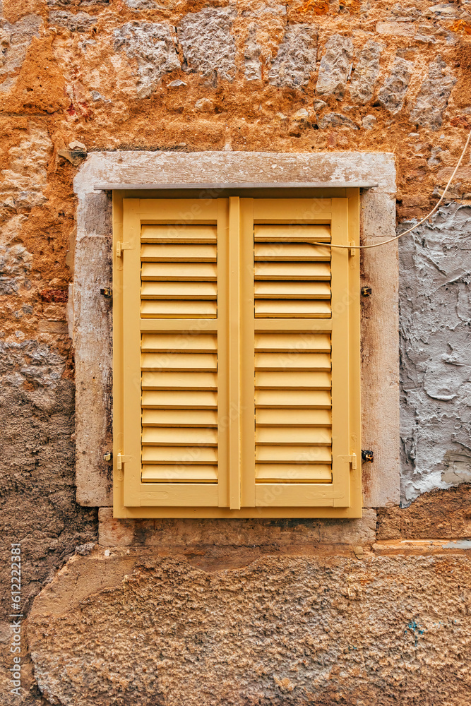Yellow window shutters of an old house in Lovran, Croatia