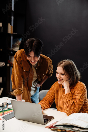 Young man and woman architects using laptop while working in office