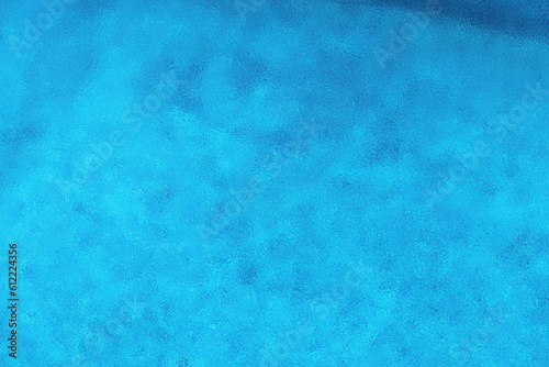 Rain drops forming circular pattern at outdoor swimming pool water surface during sudden summer shower rainfall, high angle view