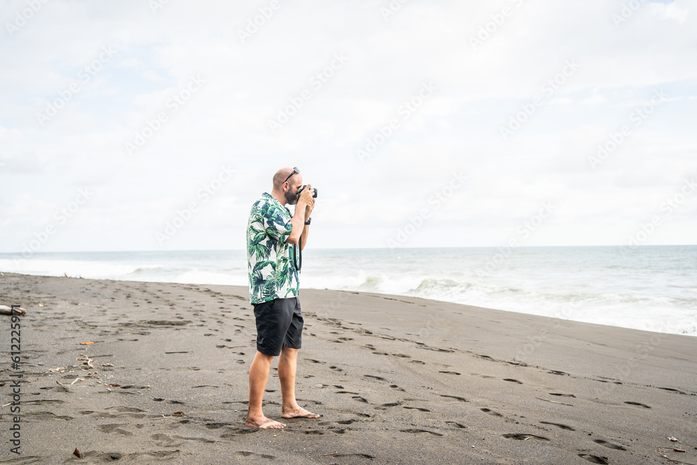 Man taking photos with digital camera on a sandy beach