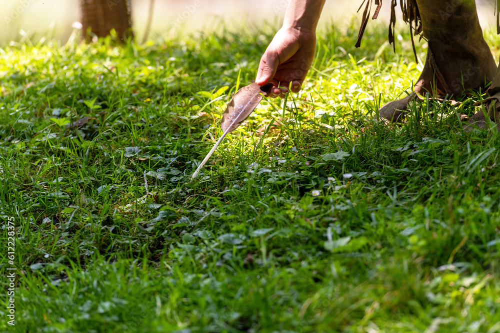 Man picks up a bird's feather in a meadow on the banks of a stream Man picks up a bird's feather in a meadow on the banks of a stream