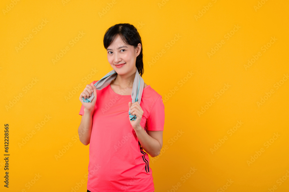 Portrait young asian sports fitness woman happy smile wearing pink sportswear and face towel doing exercise training workout against yellow studio background. wellbeing and healthy lifestyle concept. Portrait young asian sports fitness woman happy smile wearing pink sportswear and face towel doing exercise training workout against yellow studio background. wellbeing and healthy lifestyle concept.