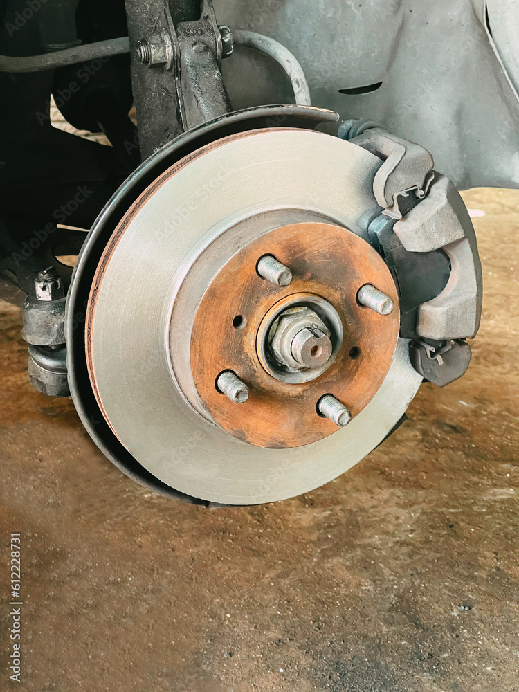 Car in the workshop changing brake discs and brake pads. Concept of work in the workshop and change of auto parts..Close up. selective focus Car in the workshop changing brake discs and brake pads. Concept of work in the workshop and change of auto parts..Close up. selective focus