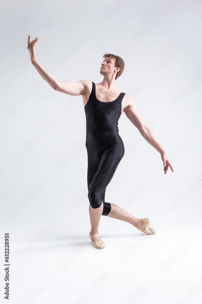 Young Athletic Caucasian Ballet Dancer Man Posing in Stretching Pose With Hands Lifted in Line and Knees Bended in Black Tights On White.