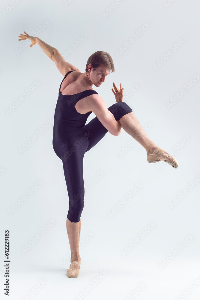 Obraz premium Toned Image of Male Ballet Dancer Man in Black Dance Suit Tights Posing in Ballanced Dance Pose While Stretching His Arm and Leg Muscles in Studio
