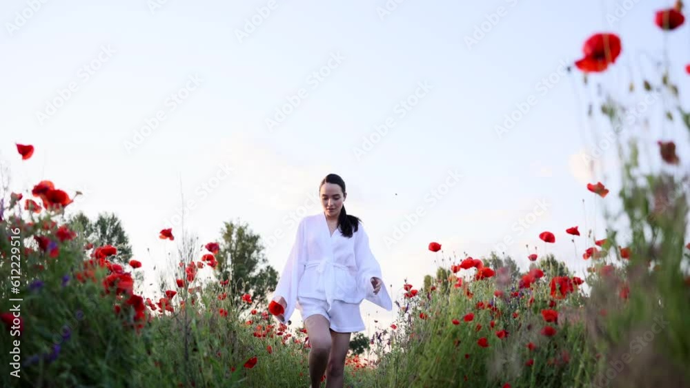 Woman with poppy flower walking and enjoying by flowering meadow at sunset. Woman with poppy flower walking and enjoying by flowering meadow at sunset.