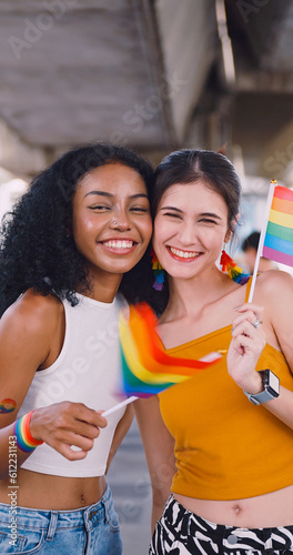 A lesbian couple waves a rainbow flag, a symbol of homosexuality, during a pride parade.