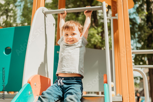 Boy hanging on slide in playground