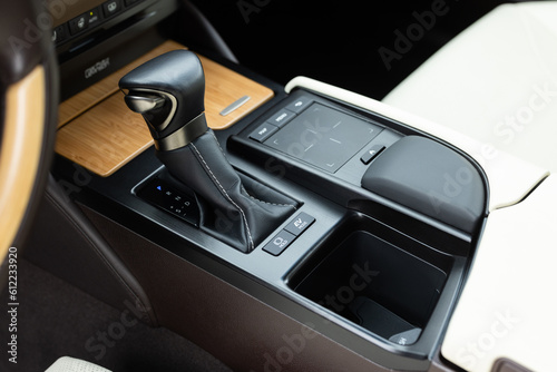 Automatic gear lever, gear shift, car interior. Luxury hybrid car interior details. Hybrid car interior console panel. Gear shift stick into P position, parking symbol in automatic transmission car