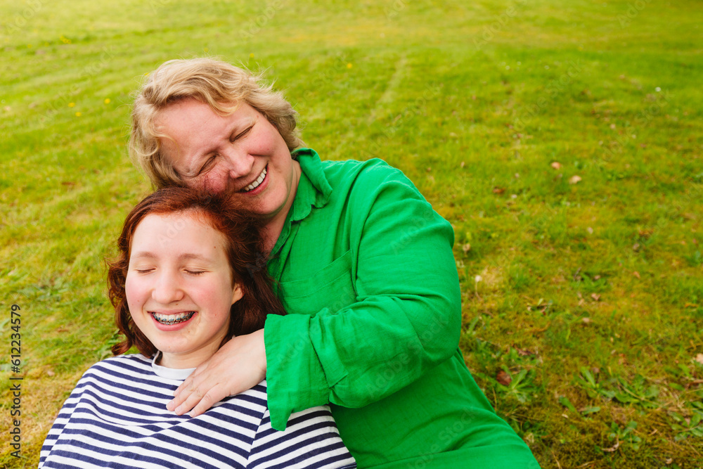 Happy mother embracing daughter sitting on grass Happy mother embracing daughter sitting on grass